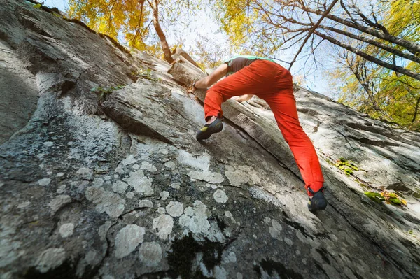 Свободный пожилой мужчина-альпинист висит на каменной стене в лесу в горах. Зрелая спортивная концепция — стоковое фото