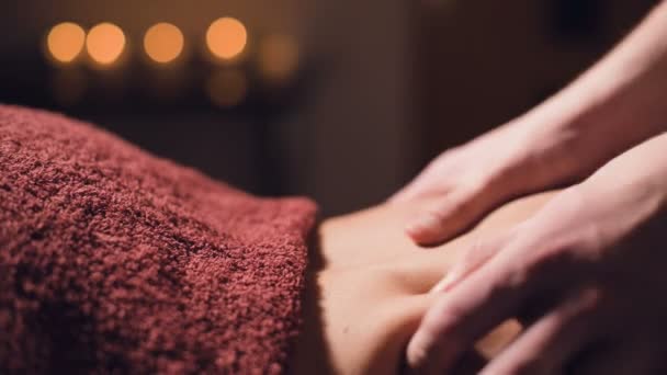 Close-up Young male massage therapist does back massage to a woman with a tattoo in a massage room with dim lights on the background of candles. Low key premium massage concept — Stockvideo