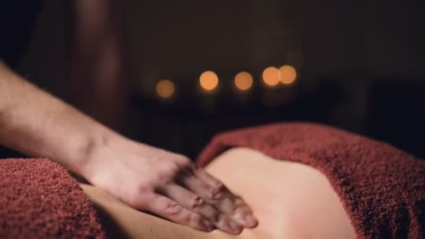 Close-up hands Masaje profesional premium en un gabinete atmosférico oscuro. Joven hombre haciendo masaje a una cliente femenina en una oficina oscura en el fondo de velas encendidas — Vídeos de Stock