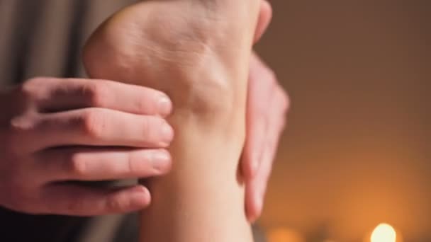 Крупним планом Професійний фізіотерапевт чоловічий масажист в офісі з затишним темним освітленням робить оздоровчий масаж стопи для жіночого клієнта. Терапевтичний масаж ніг і ніг — стокове відео