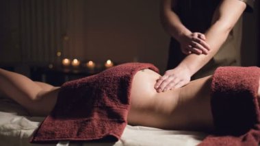 Karanlık bir atmosferik dolapta profesyonel özel masajcılar. Genç bir adam karanlık bir ofiste, mum yakmanın arka planında bayan bir müşteriye masaj yapıyor.