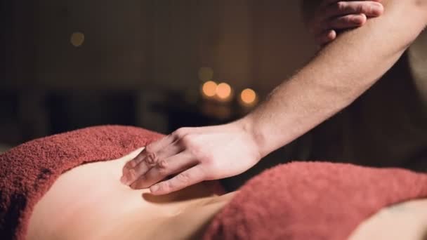 Close-up hands Masaje profesional premium en un gabinete atmosférico oscuro. Joven hombre haciendo masaje a una cliente femenina en una oficina oscura en el fondo de velas encendidas — Vídeos de Stock