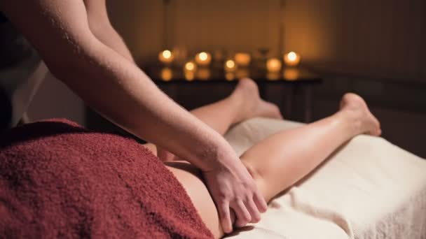 Close-up van premium anti-cellulitis dijmassage. Mannelijke handen doen wellness massage van de dij aan het geduldige meisje in een gezellige studie met schemerig licht. Luxe massagediensten — Stockvideo