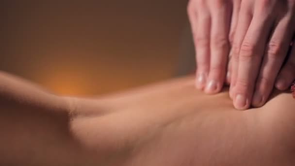 Close-up de massagem premium anti-celulite na coxa. As mãos masculinas fazem a massagem de bem-estar da coxa à menina paciente em um estudo acolhedor com a luz escura. Serviços de massagens de luxo — Vídeo de Stock