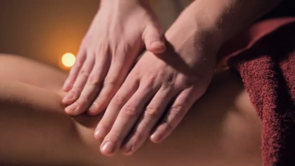 Close-up van premium anti-cellulitis dijmassage. Mannelijke handen doen wellness massage van de dij aan het geduldige meisje in een gezellige studie met schemerig licht. Luxe massagediensten — Stockvideo