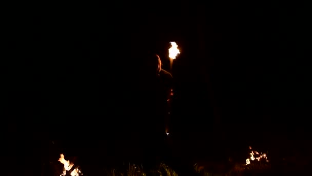 Молодой человек в темноте изображает вращающийся горящий факел. Пожарное шоу. Низкий ключ . — стоковое видео