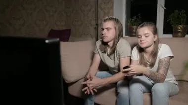 Genç çift televizyon izliyor. Erkek kanal değiştirir, kadın kontrolü seçer..