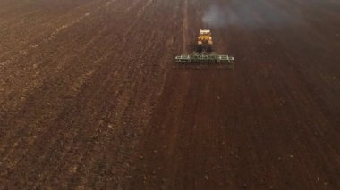 Tahıl ekmeden önce tarla süren sarı bir traktörün havadan görünüşü. Toprağı toprağa tohum ekmeye hazırlama kavramı. Çiftlik