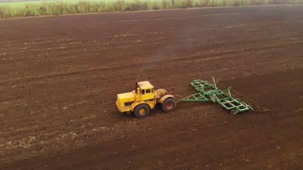 Vue aérienne d'un puissant tracteur jaune avec un grand effort sur le crochet effectuant le labour pour semer des cultures d'hiver avec un cultivateur à disque à l'automne 