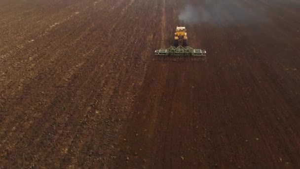 Vue aérienne d'un tracteur jaune avec une remorque labourant une terre labourant un champ cultivé avant de planter des céréales. Le concept de préparation de la terre pour planter des graines dans le sol. Exploitation agricole 