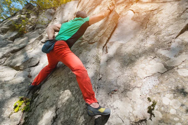 Ein frei gealterter männlicher Kletterer hängt an einer Felswand in einem Wald in den Bergen. Reifes Sportkonzept — Stockfoto