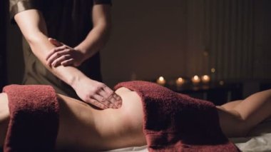 Karanlık bir atmosferik dolapta profesyonel özel masajcılar. Genç bir adam karanlık bir ofiste, mum yakmanın arka planında bayan bir müşteriye masaj yapıyor.