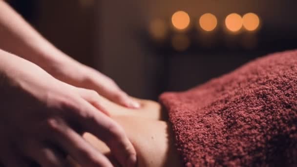 Крупный план Молодой массажист-мужчина делает массаж спины женщине с татуировкой в массажной комнате с тусклыми лампами на фоне свечей. Низкий ключ премиум массаж — стоковое видео