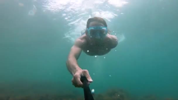 Hombre musculoso con máscara nada bajo el agua, sosteniendo la cámara delante. Primer plano . — Vídeos de Stock