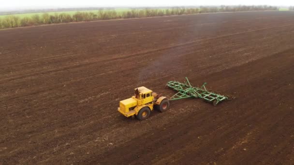 Vue aérienne d'un puissant tracteur jaune avec un grand effort sur le crochet effectuant le labour pour semer des cultures d'hiver avec un cultivateur à disque à l'automne 