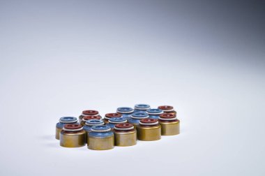 İçten yanmalı motor için yeni yedek parça. Egzoz ve solenoid kapakçıklarından oluşan yağ kapakları. Gri arka planda bir sürü yağ mühürü var.