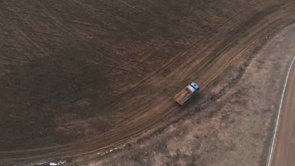 Вид с воздуха на пустой грузовик, едущий по грунтовой дороге. Концепция строительных работ и утилизация строительных отходов — стоковое видео