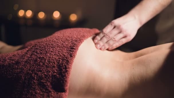 Zbliżenie dłonie Profesjonalny masaż premium w ciemnej szafie atmosferycznej. Młody mężczyzna robi masaż kobiecie klientce w ciemnym biurze na tle palących się świec — Wideo stockowe