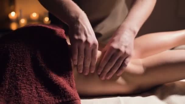 Nahaufnahme einer erstklassigen Anti-Cellulite-Schenkelmassage. Männliche Hände massieren in einer gemütlichen Studie mit schummrigem Licht den Oberschenkel der Patientin. Luxusmassagen