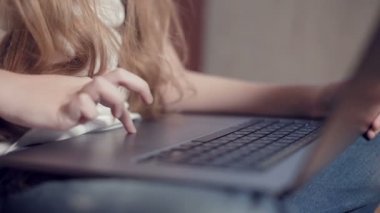 Laptop klavyesinde küçük bir kızın elinin sığ derinliği. Genç nesil aletleri kullanma fikri.
