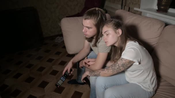 La giovane coppia sta guardando la TV. La donna cambia canale, l'uomo seleziona il controllo . — Video Stock