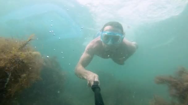 Мускулистый человек в маске плавает под водой, держа перед собой камеру. Крупный план . — стоковое видео