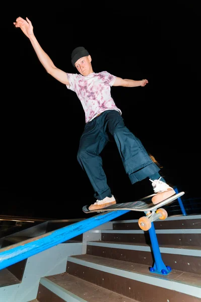 Un patinador joven por la noche en un skatepark hace el truco en la barandilla. Cultura de rayos X concepto de vida nocturna — Foto de Stock