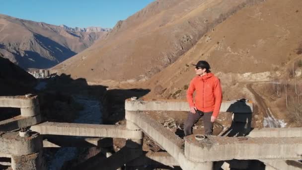 Vista aérea de um macho ruffer extremo sentado no topo de estruturas de proteção de alto fluxo de lama nas montanhas durante o dia. O conceito de proteção contra lama e tipos extremos de recreação e coberturas — Vídeo de Stock