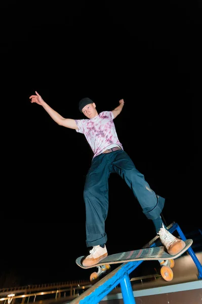 一个年轻的滑板手晚上在一个滑板公园里做的把戏在栏杆上。X光文化夜生活概念 — 图库照片