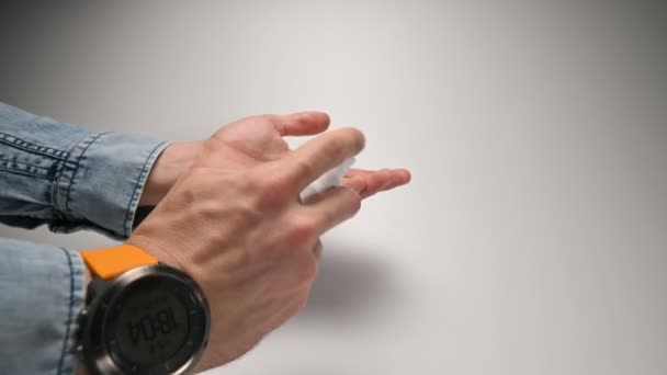 Close-up mannelijke handen in een blauw denim shirt met een gele band en een horloge met behulp van een ontsmettingsmiddel spray een antisepticum om het oppervlak van de handpalmen te behandelen en vervolgens een duim omhoog gebaar tonen. — Stockvideo