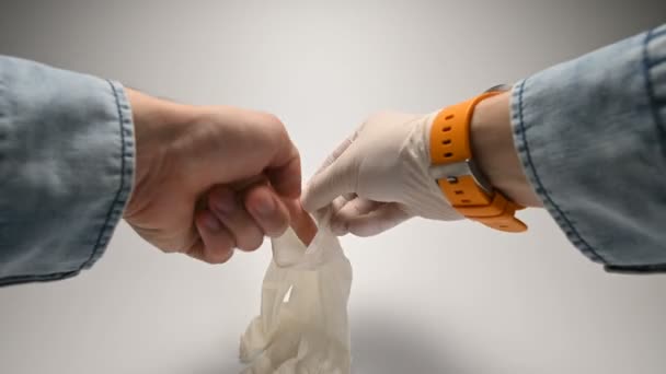 Gros plan vue à la première personne les mains des hommes dans une chemise en denim bleu et une montre avec un bracelet jaune sur leur main droite portent des gants médicaux de protection en caoutchouc . — Video