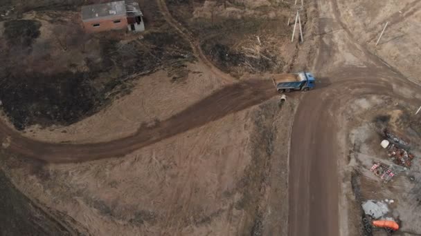 Toprak yolda giden boş bir çöp kamyonunun hava görüntüsü. İnşaat işi ve inşaat atığının imhası kavramı — Stok video