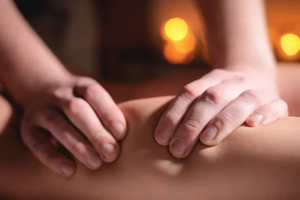 Close-up van de handen van een professionele massage therapeut mannen doen wellness massage shins en benen voor een klant om een meisje in een professionele massage salon op de achtergrond van brandende kaarsen — Stockfoto