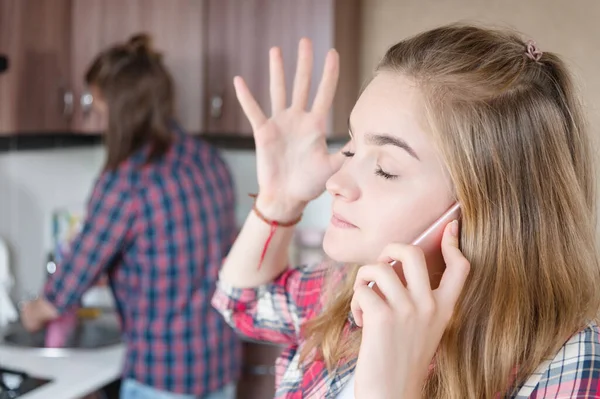 Una mujer de pelo largo está molesta hablando por teléfono o llamando al servicio de entrega de alimentos y medicamentos a casa de pie en la cocina. — Foto de Stock