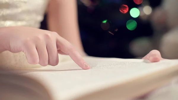 La main étroite d'une petite fille mène une lecture de livre et étudie le texte. Le concept d'apprentissage à domicile lors d'une pandémie virale — Photo