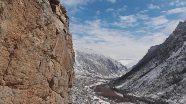 Una vista aérea de la envergadura junto a la roca en el desfiladero de la montaña a principios de primavera empolvada de nieve. — Vídeo de stock