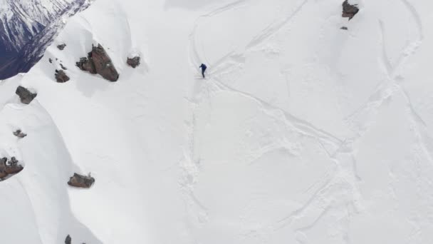 Widok z lotu ptaka narciarz jeździ freeride na stromym stoku. Profesjonalne narty ekstremalne w górach Alp lub na Północnym Kaukazie — Wideo stockowe