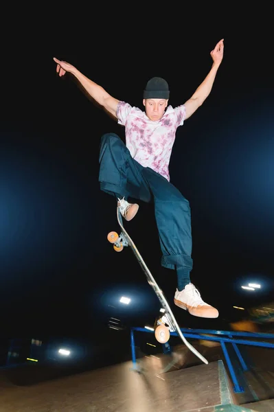 Młody skatecrack w nocnym skateparku skacze na halfpipe. Kultura młodzieżowa Pojęcie czasu wolnego w nocy — Zdjęcie stockowe