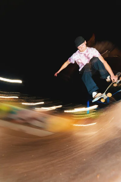 Um jovem patinador à noite em um parque de skate faz o truque no corrimão. Conceito de vida noturna de cultura de raios-X — Fotografia de Stock