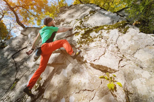 Ein alter bärtiger Mann trainiert an einem sonnigen Tag auf einem Felsen im Wald im Freiklettern. Das Konzept der Freizeitaktivitäten eines aktiven Lebensstils von Menschen im Alter — Stockfoto