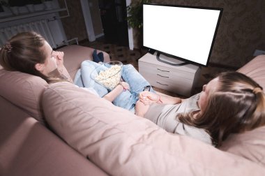 Çekici, genç, uzun saçlı bir çift, izole bir şekilde evde bir kanepede sarılıyorlar ve televizyon izliyorlar. Bir salgın sırasında sevdiklerinle vakit geçirme kavramı..
