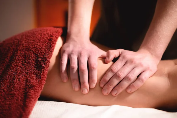 Close-up male hands of a professional massage therapist make professional anti-cellulite massage to a female client in a specialized salon in a dark room — Stock Photo, Image