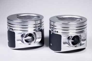 Close-up of two new internal combustion engine piston on a gray gradient background. The concept of new spare parts of the internal combustion engine clipart