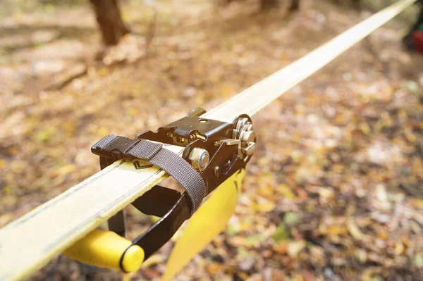 Εξοπλισμός για χαλαρό ιμάντα Slackline δίπλα στο μηχάνημα και προστασία για το δέντρο. τεντωμένο κίτρινο χρώμα slackline το φθινόπωρο δάσος — Φωτογραφία Αρχείου