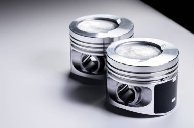 Gri bir arka planda iki yeni içten yanmalı motor pistonunun yakın çekimi. İçten yanmalı motorun yeni yedek parçaları kavramı