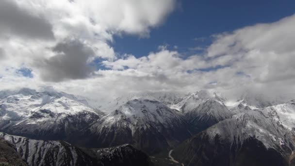 4K timelapsewide γωνία ψηλά πάνω από το φαράγγι επιπλέουν γρήγορα σύννεφα που καλύπτουν τις χιονισμένες κορυφές των ψηλών βουνών. Η έννοια της αλλαγής του καιρού στα βουνά κάτω από το χωριό φαράγγι — Αρχείο Βίντεο
