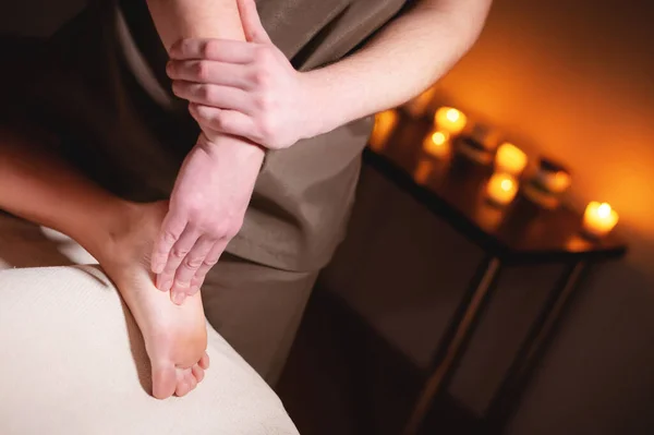 Profesionální masáž chodidel v tmavé masážní místnosti. Premium lacheri masáž nohou. Mužský masér masíruje nohy a chodidla klienta — Stock fotografie