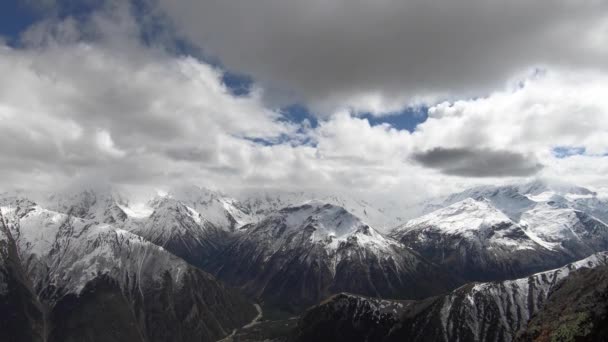 4K timelapsewide γωνία ψηλά πάνω από το φαράγγι επιπλέουν γρήγορα σύννεφα που καλύπτουν τις χιονισμένες κορυφές των ψηλών βουνών. Η έννοια της αλλαγής του καιρού στα βουνά κάτω από το χωριό φαράγγι — Αρχείο Βίντεο