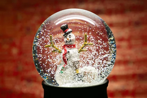 Invierno globo de nieve con muñeco de nieve en rojo — Foto de Stock