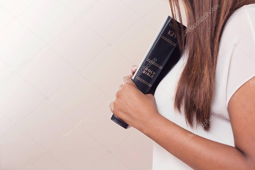 Young Lady Holding Her Bible Close To Her Heart
